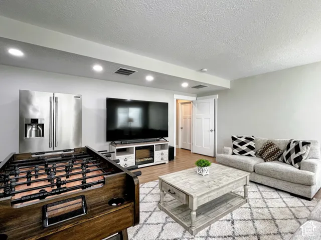 Recessed lighting illuminates the space, featuring a stainless steel refrigerator and wood-finish flooring