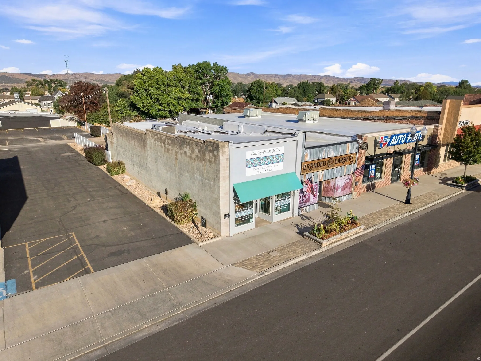 Commercial building with a paved parking area, sidewalk frontage, and a mountain backdrop