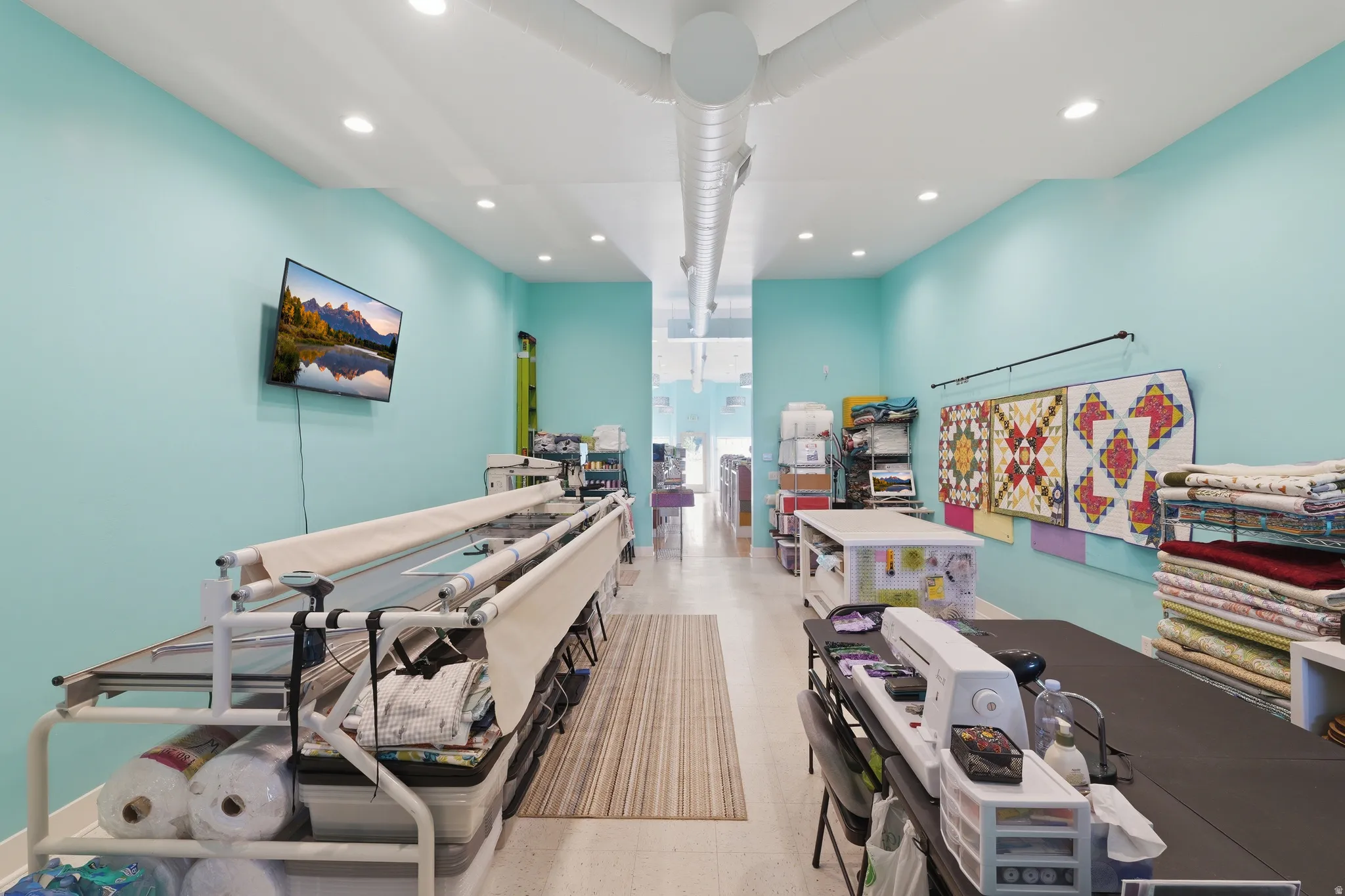 Recessed lighting, light-toned flooring, exposed ceiling ductwork, and abundant ambient light