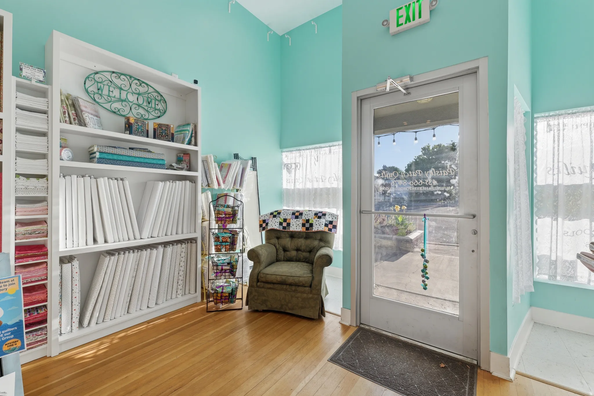 Wood-finish flooring with a full-light entry door, white built-in shelving, and light blue wall color