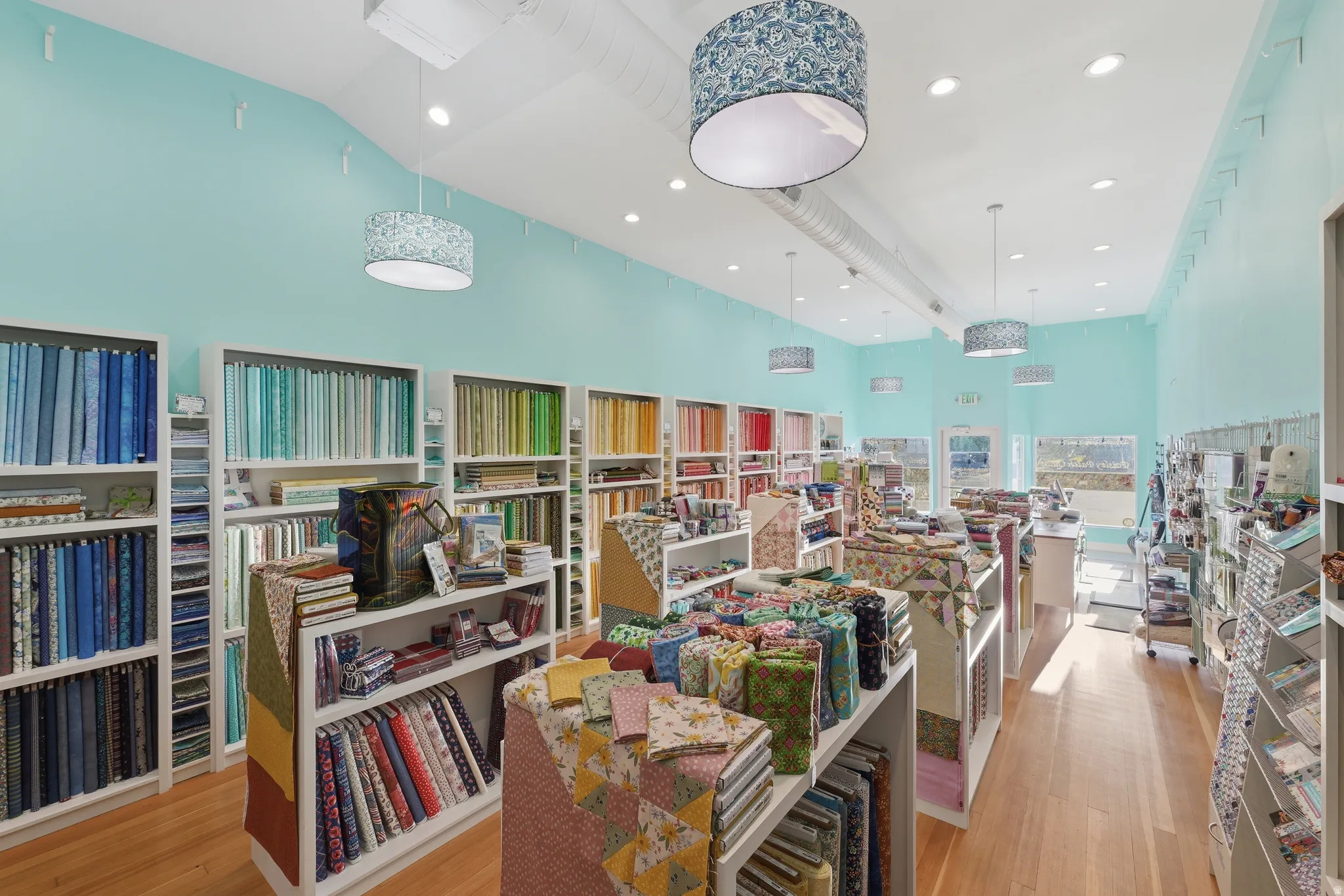Light wood-finish flooring, recessed ceiling lighting, and multiple pendant light fixtures