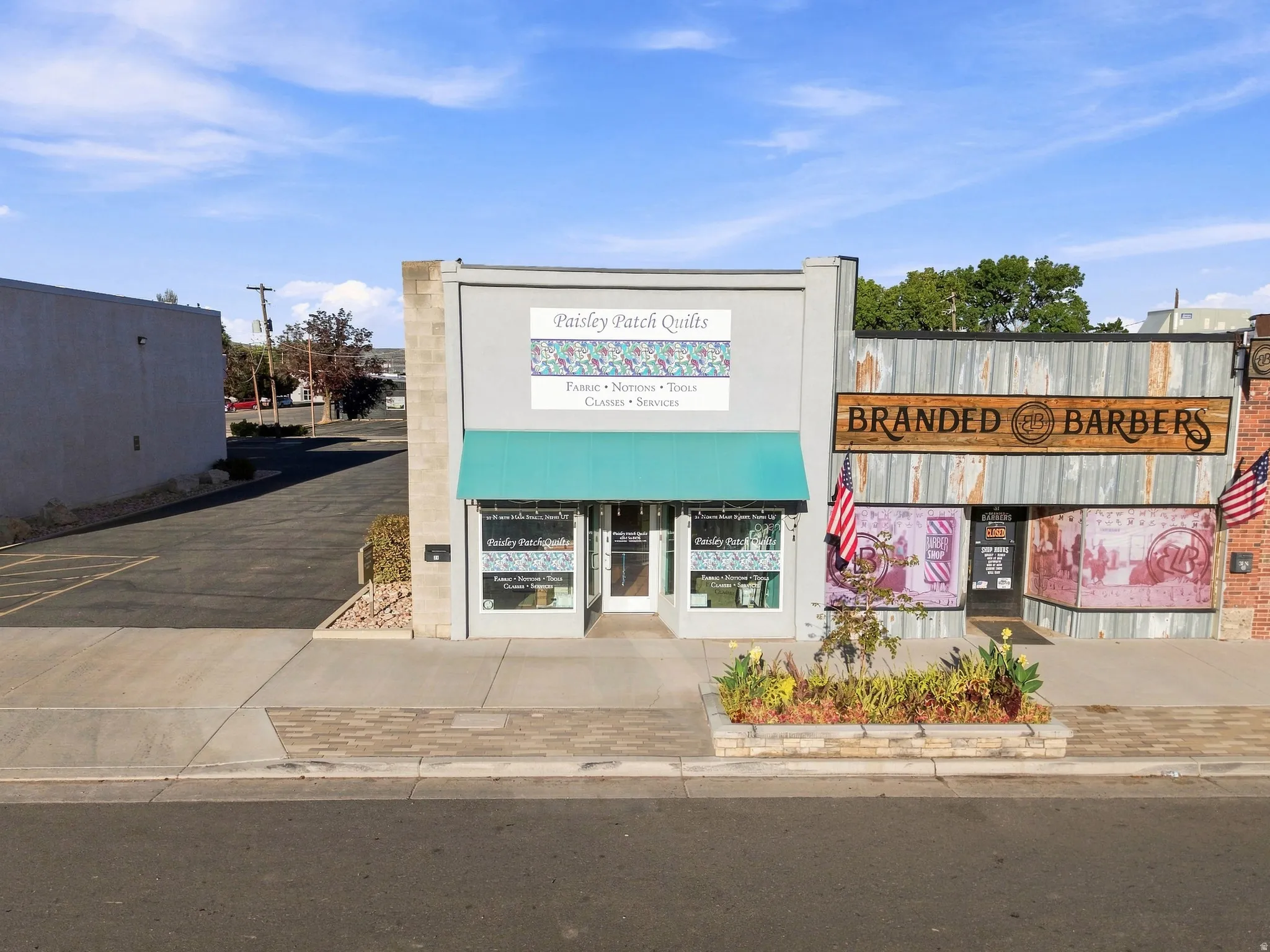 Storefront entry with transom windows, a green fabric awning, and a stone-clad planter box