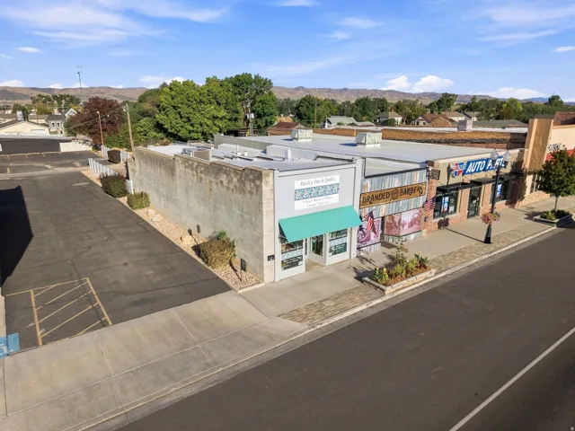 Commercial building with a paved parking area, sidewalk frontage, and a mountain backdrop