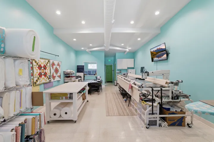 Recessed lighting, exposed ductwork, a mounted flat-screen display, and a green door