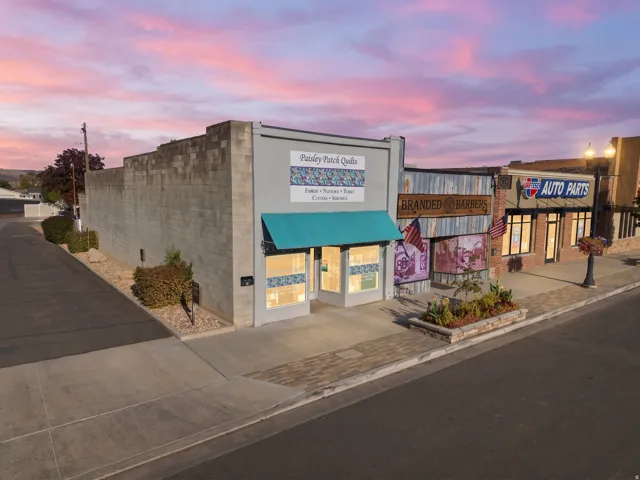 Commercial building with a prominent storefront, teal awning, and an adjacent block wall structure