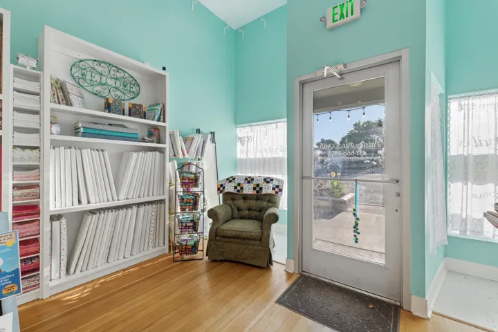 Wood-finish flooring with a full-light entry door, white built-in shelving, and light blue wall color
