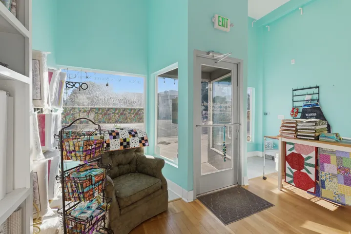 Light wood-finish flooring, high ceilings, large storefront windows, and a glass-paneled entry door