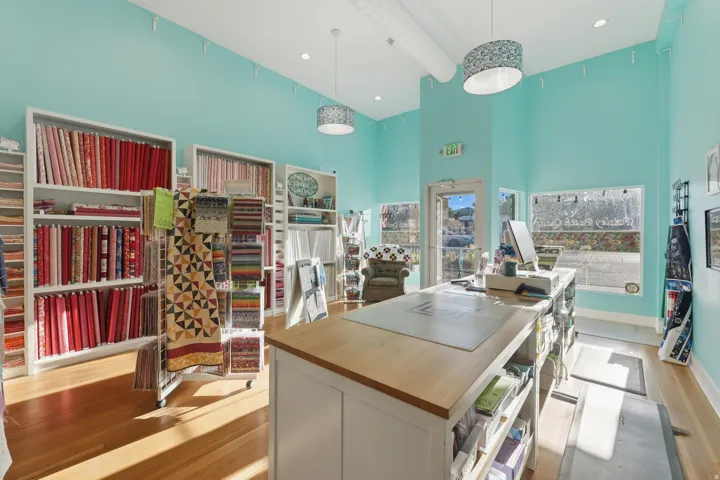Wood-finish flooring, high ceilings, recessed lighting, and expansive storefront windows