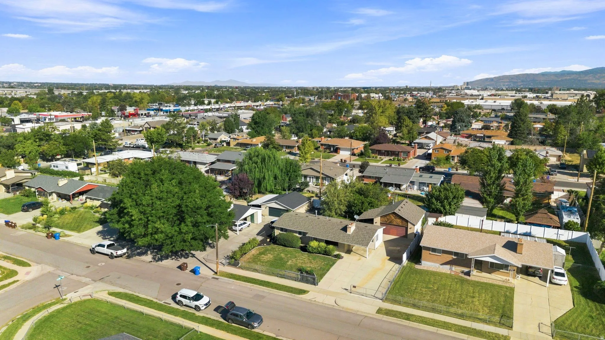 Residential neighborhood with mature trees and a clear mountain backdrop