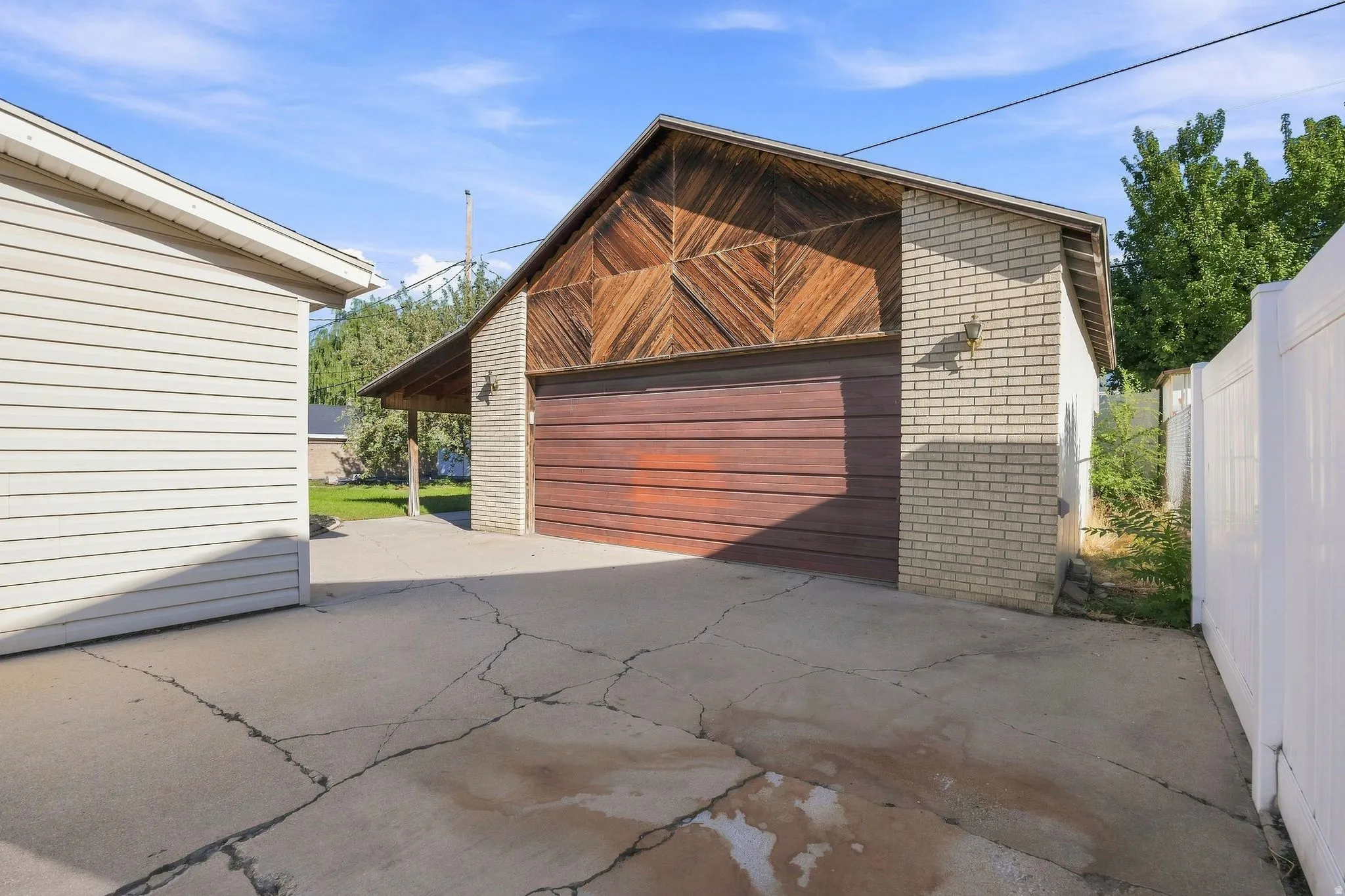 Detached garage with brick facade, hard crafted wood siding, and an attached covered patio.