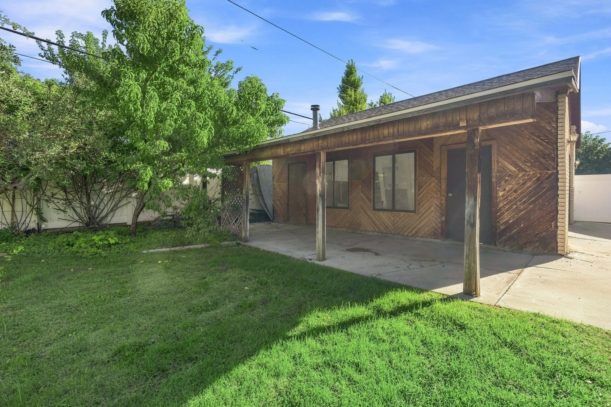 Handcrafted wood-paneled, covered patio, concrete slab, and a grassy entertainment yard