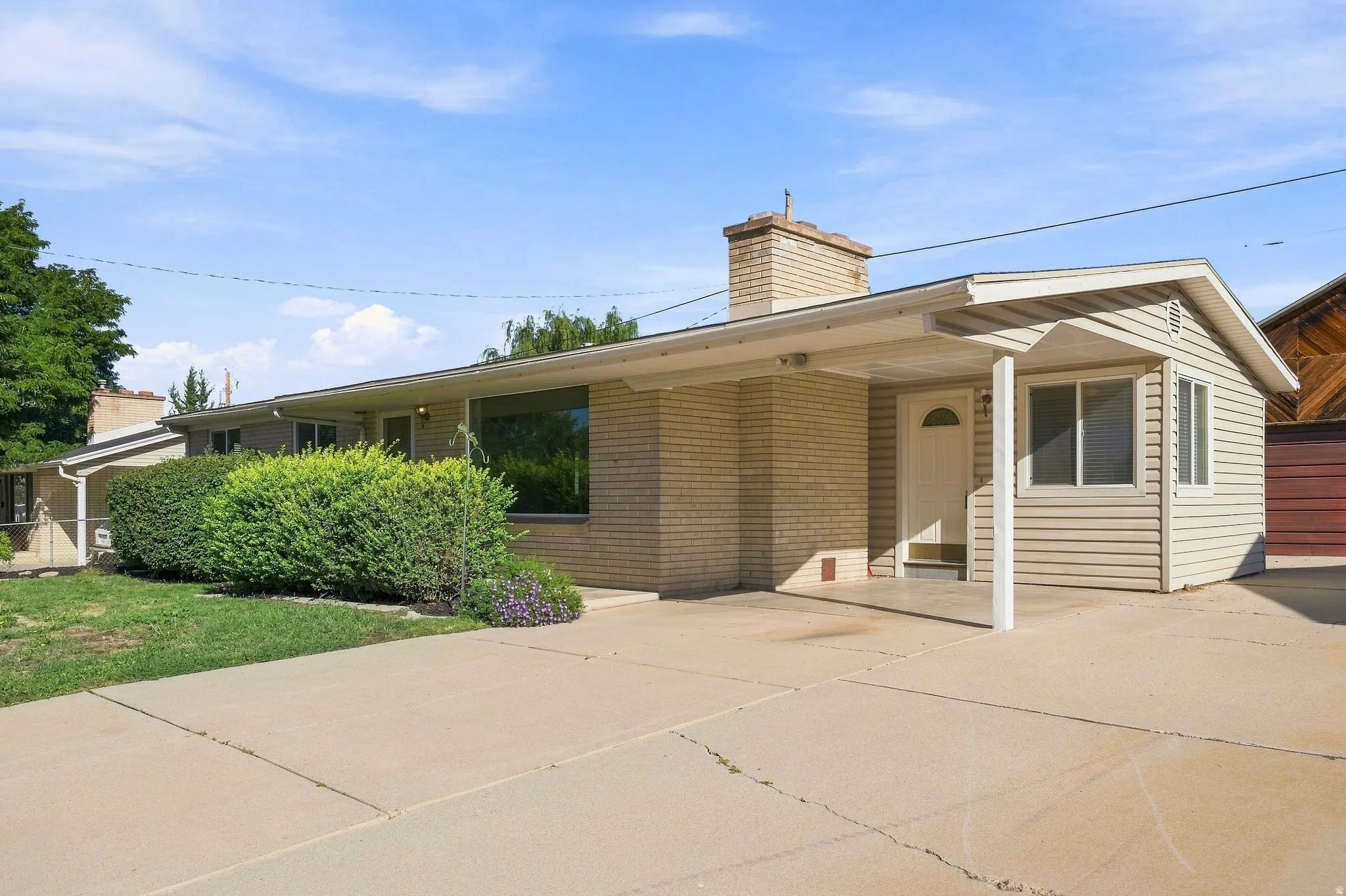Brick and siding exterior with a covered entry, established landscaping, a concrete driveway, and large RV parking.