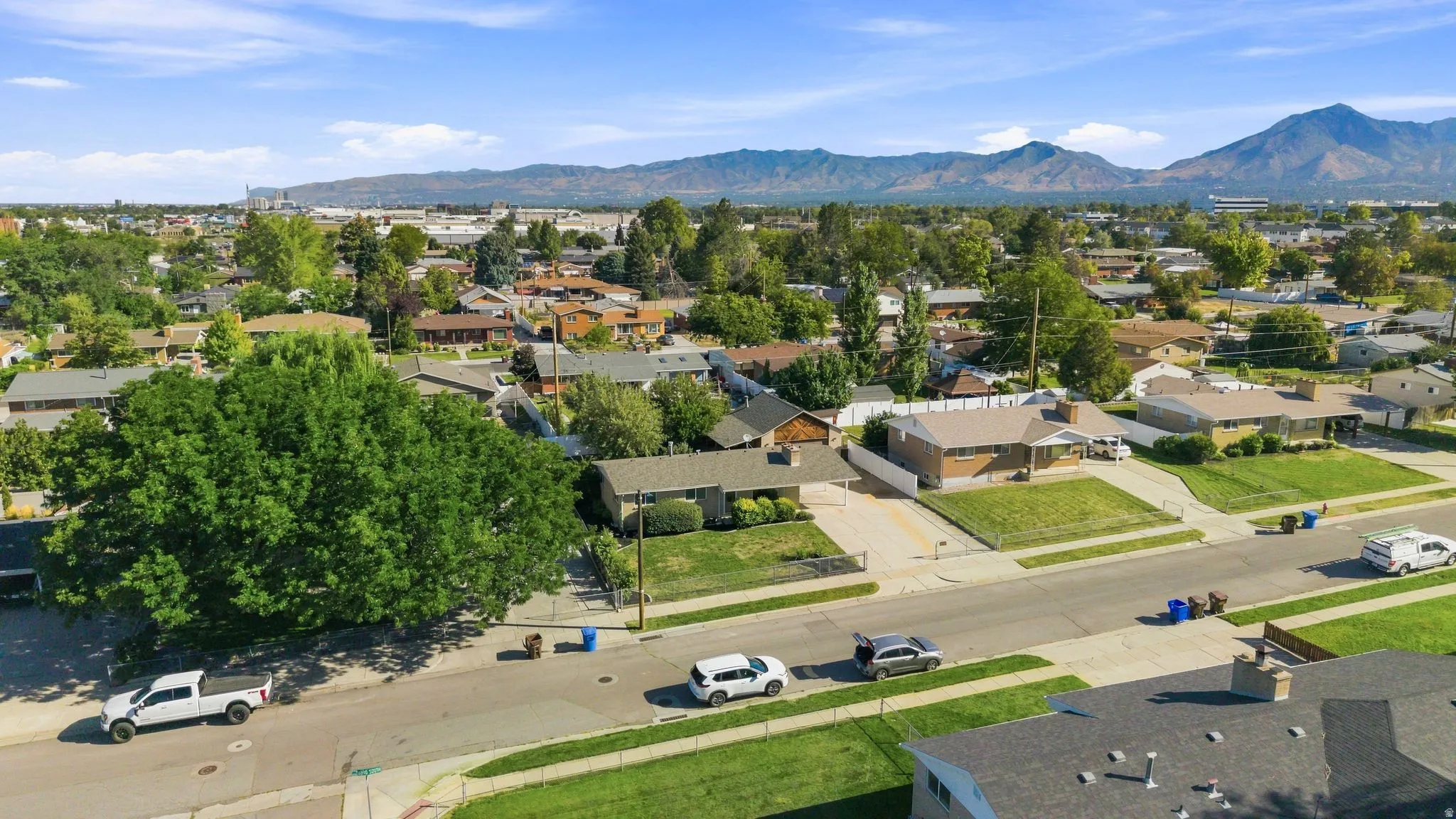Residential neighborhood with mature trees, paved streets, and distinct mountain ranges