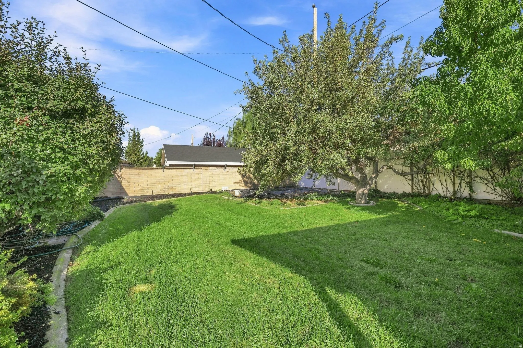 Expansive lawn with mature trees and a brick privacy wall