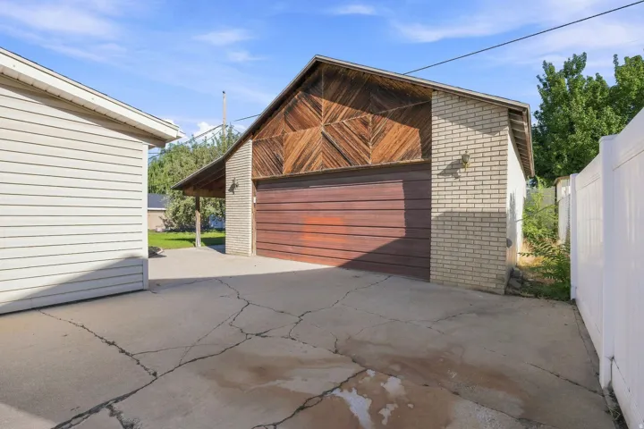 Detached garage with brick facade, hard crafted wood siding, and an attached covered patio.