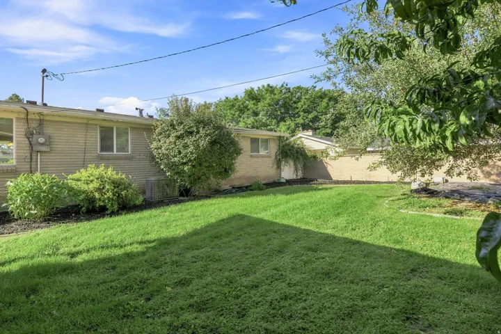 Expansive lawn area, mature trees, brick exterior, and established landscaping