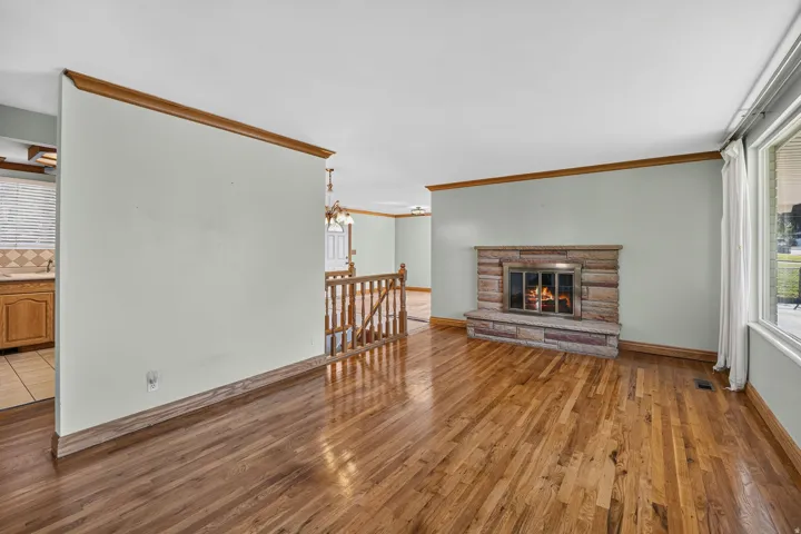 Old-growth-forest Hardwood flooring, stone fireplace, picture  window, wooden railing.