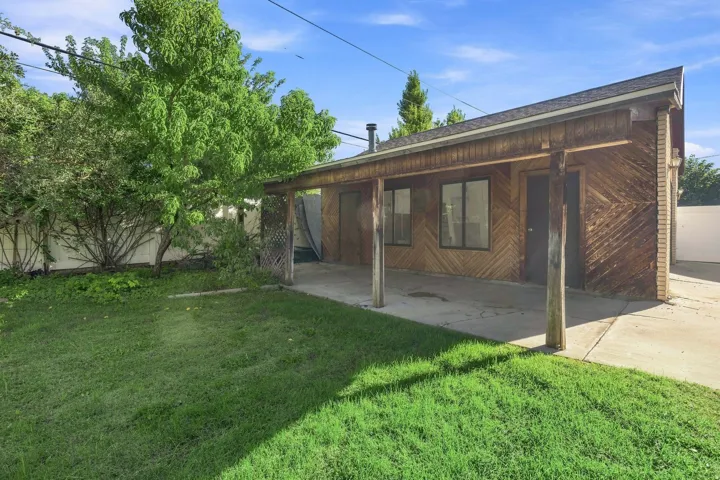 Handcrafted wood-paneled, covered patio, concrete slab, and a grassy entertainment yard