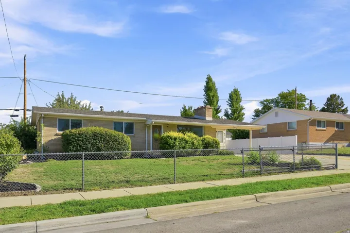 Brick exterior with a covered entryway, covered front patio and porch, chain-link fencing, and mature landscaping