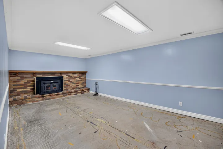 Cozy, fireplace, featuring exposed brick fireplace with dark surround, recessed and panel lighting throughout, light blue accent walls with chair rail molding