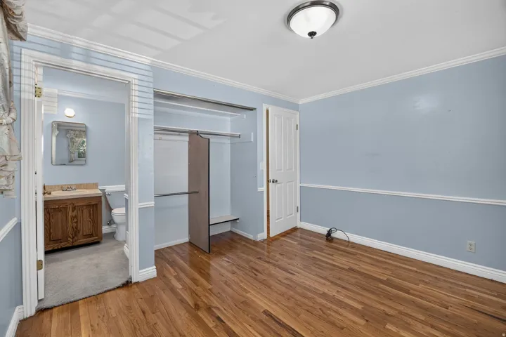 Primary Suite with Hardwood flooring, crown molding, chair rail molding, built-in closet storage, and a semi-flush mount ceiling light