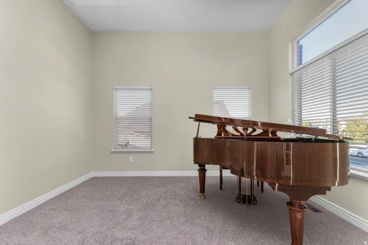 High ceilings with a rectangular ceiling access panel, neutral wall finishes, gray carpeting, and multiple windows with horizontal blinds