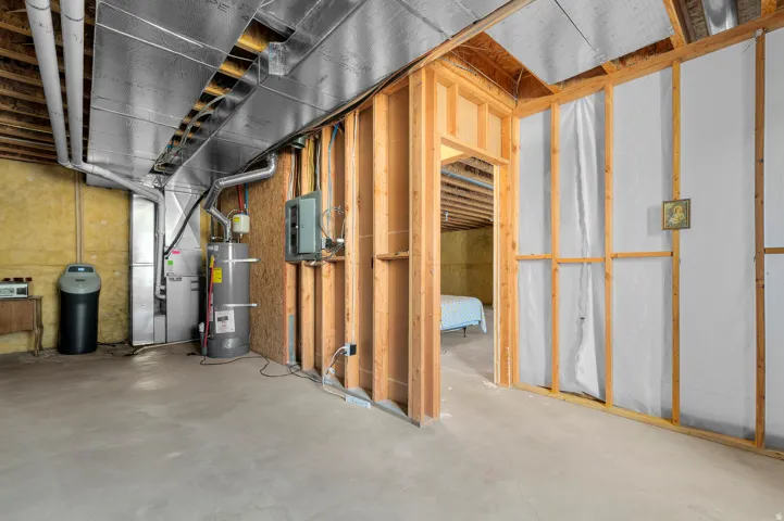 Unfinished basement with concrete flooring, exposed ceiling joists, and framed partition walls