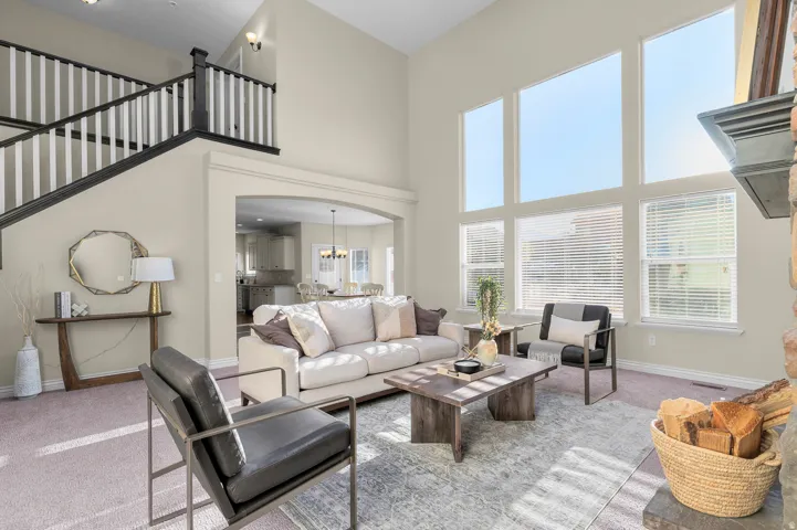 Two-story living area with high ceilings, multiple tall windows, a staircase with white spindles, and an arched entryway