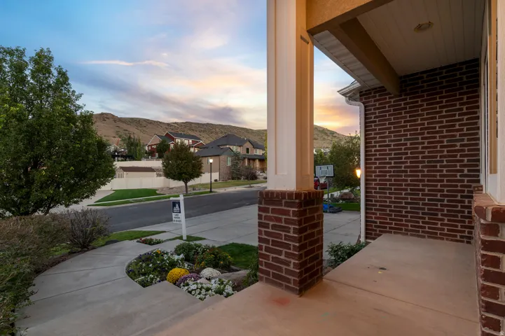 Brick exterior with white trim, concrete porch, and front garden landscaping
