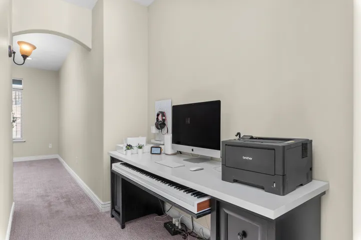 Built-in desk with a light-toned countertop, integrated cabinetry, and an arched hallway entry