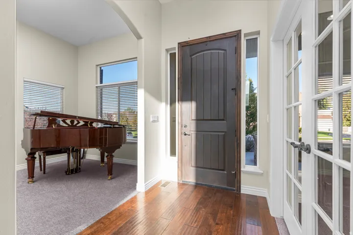 Hardwood entry flooring, arched doorway, French doors, dark wood front door, and natural light