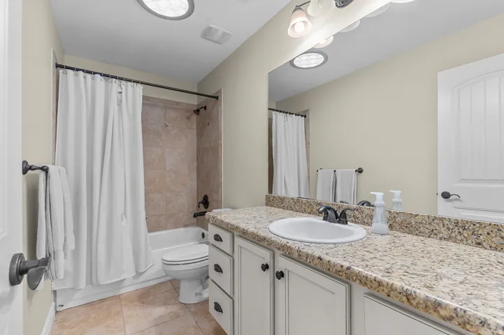 Bathroom featuring a vanity with a granite countertop, white cabinetry, undermount sink, and a tiled shower/tub combination