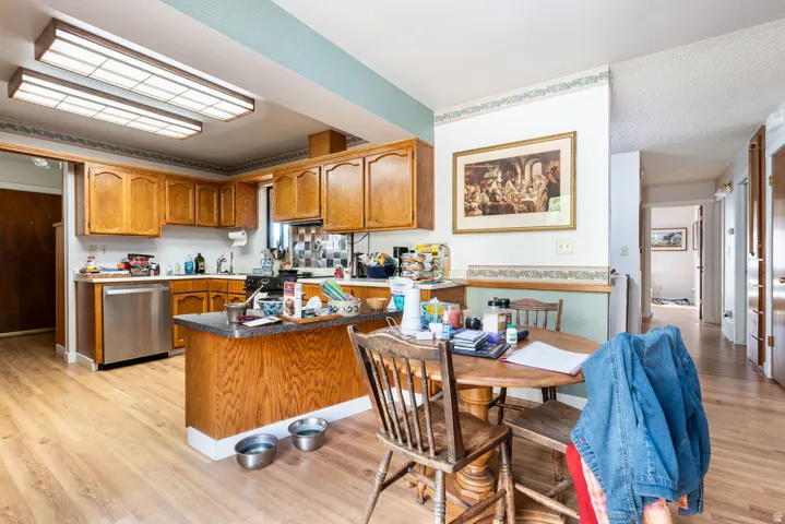 Kitchen featuring wood-finish cabinetry, stainless steel dishwasher, and a center island with a stone-finish countertop