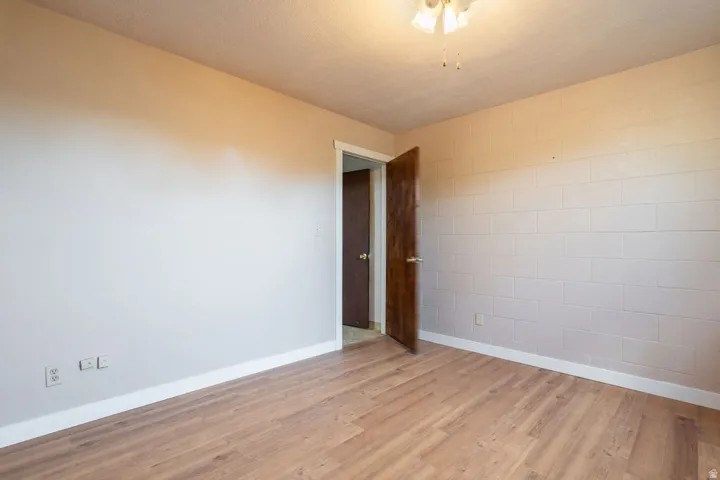 Wood-finish flooring with white trim and a painted block wall