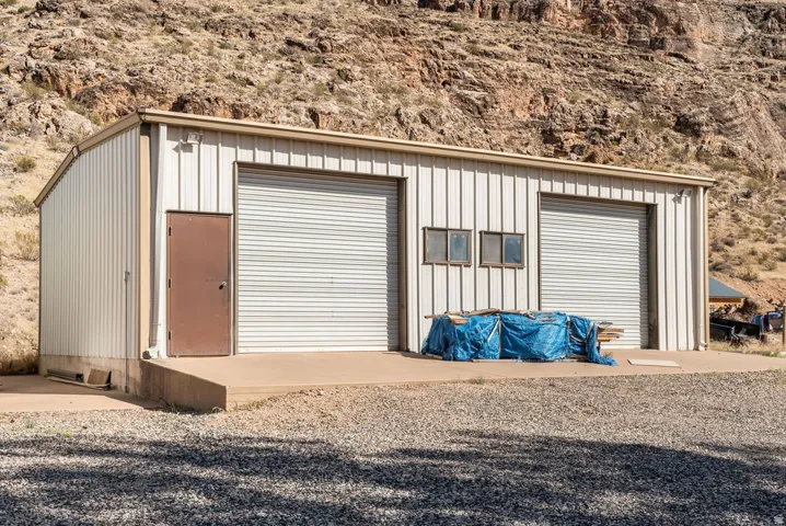 Metal-sided structure featuring two roll-up garage doors, a pedestrian entrance, and two windows