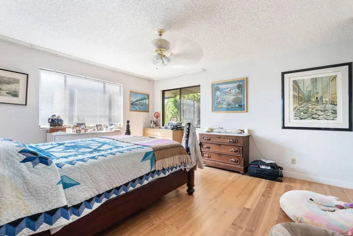 Recessed window with horizontal blinds, wood-finish flooring, ceiling fan with light fixture, and white walls