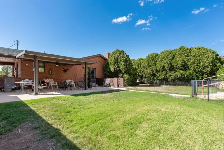 Expansive backyard featuring a covered patio, brick exterior, and mature trees