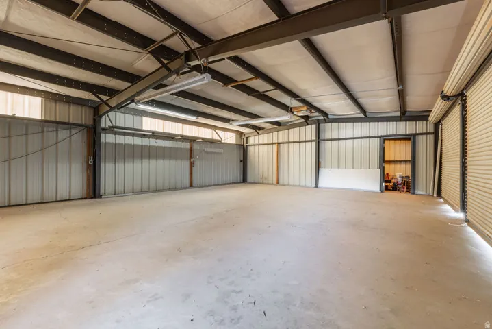 Expansive concrete floor space with exposed steel beam construction, corrugated metal walls, and multiple roll-up doors