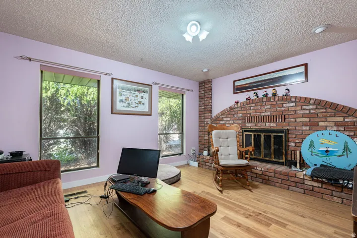 Arched brick fireplace with a black firebox, wood-finish flooring, and multiple windows