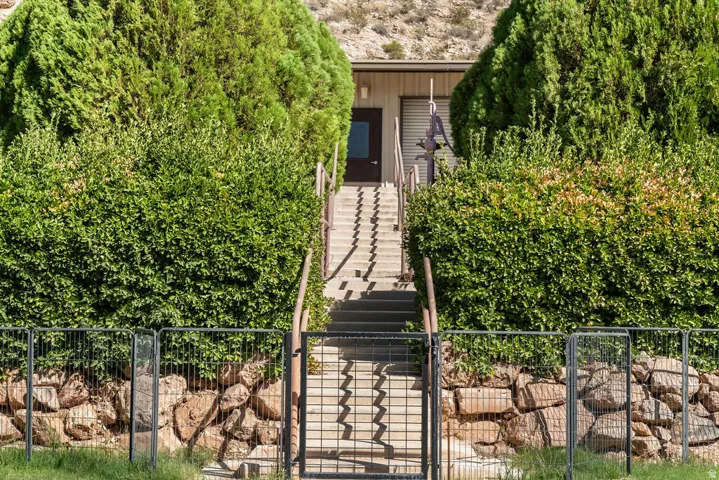 Concrete staircase with metal handrails, leading to a dark brown entry door