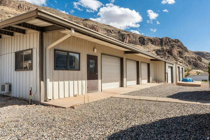 Corrugated metal siding structure featuring multiple roll-up doors, an exterior entry door, and two windows