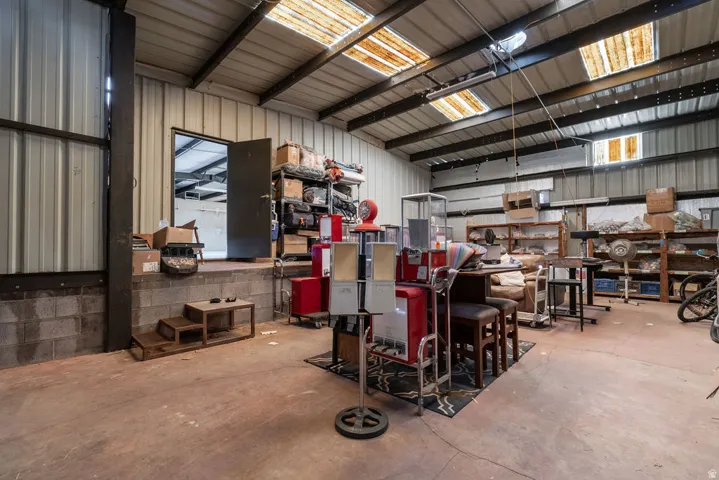 Warehouse space featuring a concrete floor, corrugated metal walls, and exposed ceiling beams with skylights