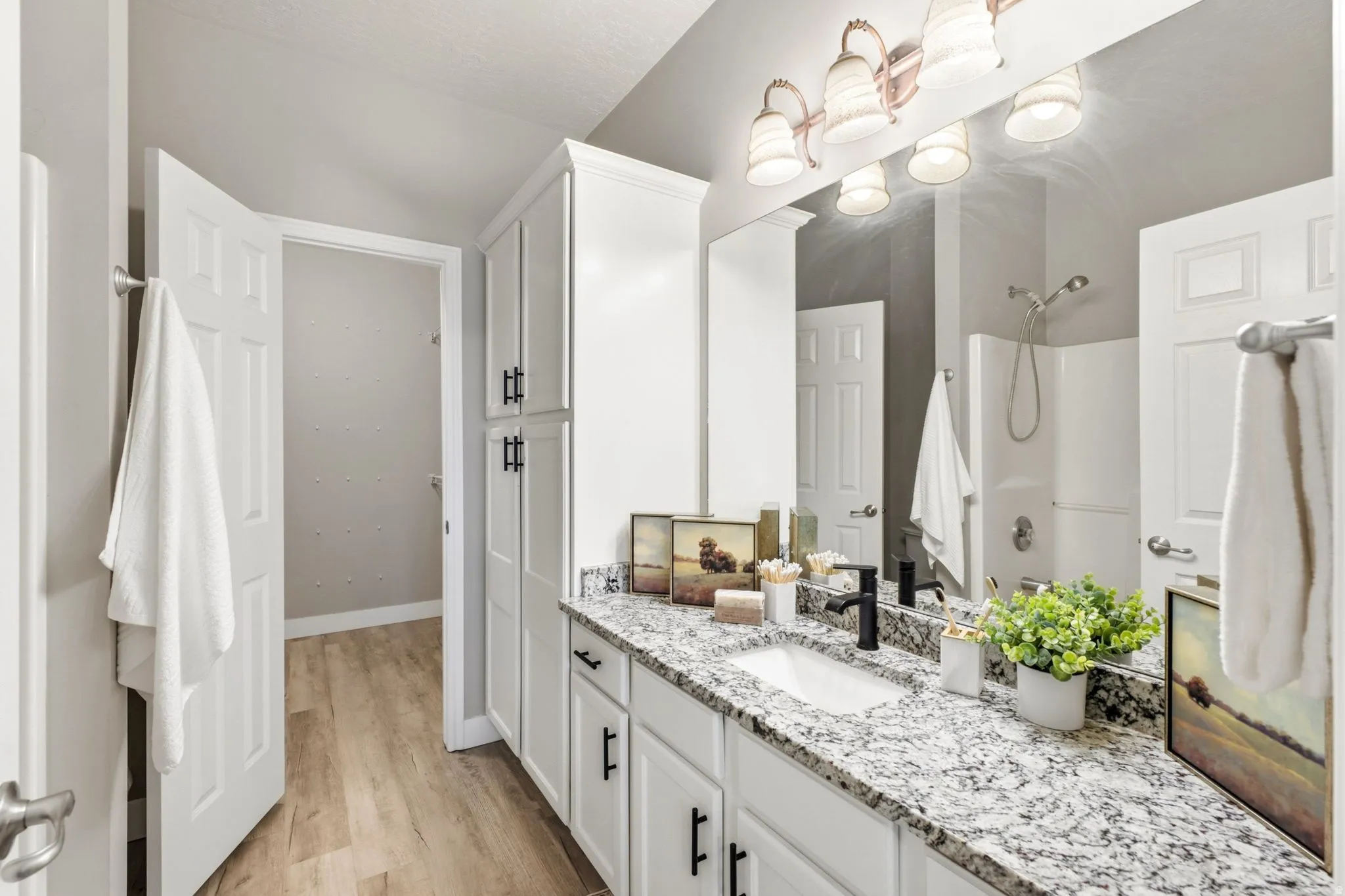 Dual vanity with white cabinetry, speckled countertop, and black fixtures