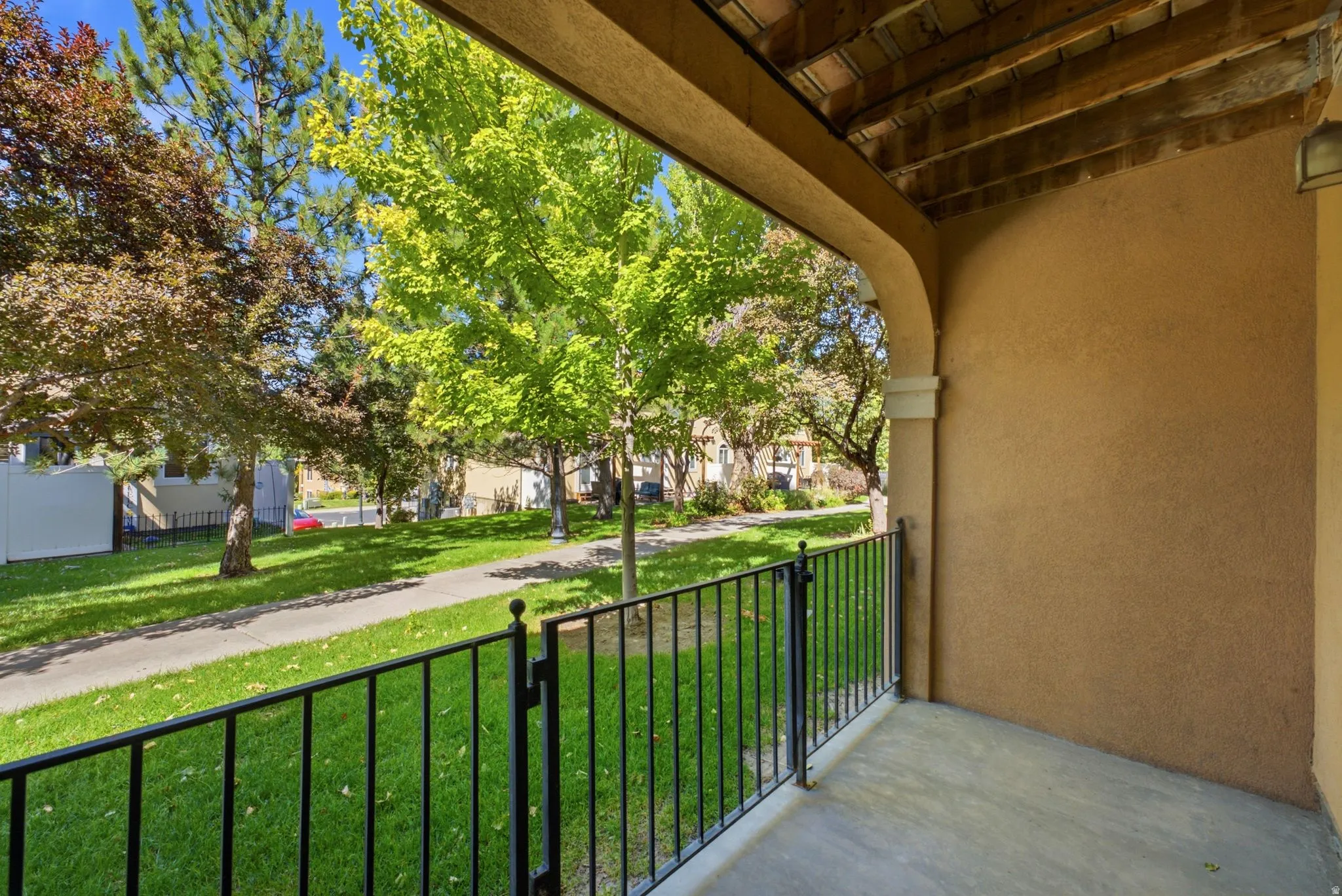 Covered exterior balcony with a concrete floor, stucco walls, and an arched entryway