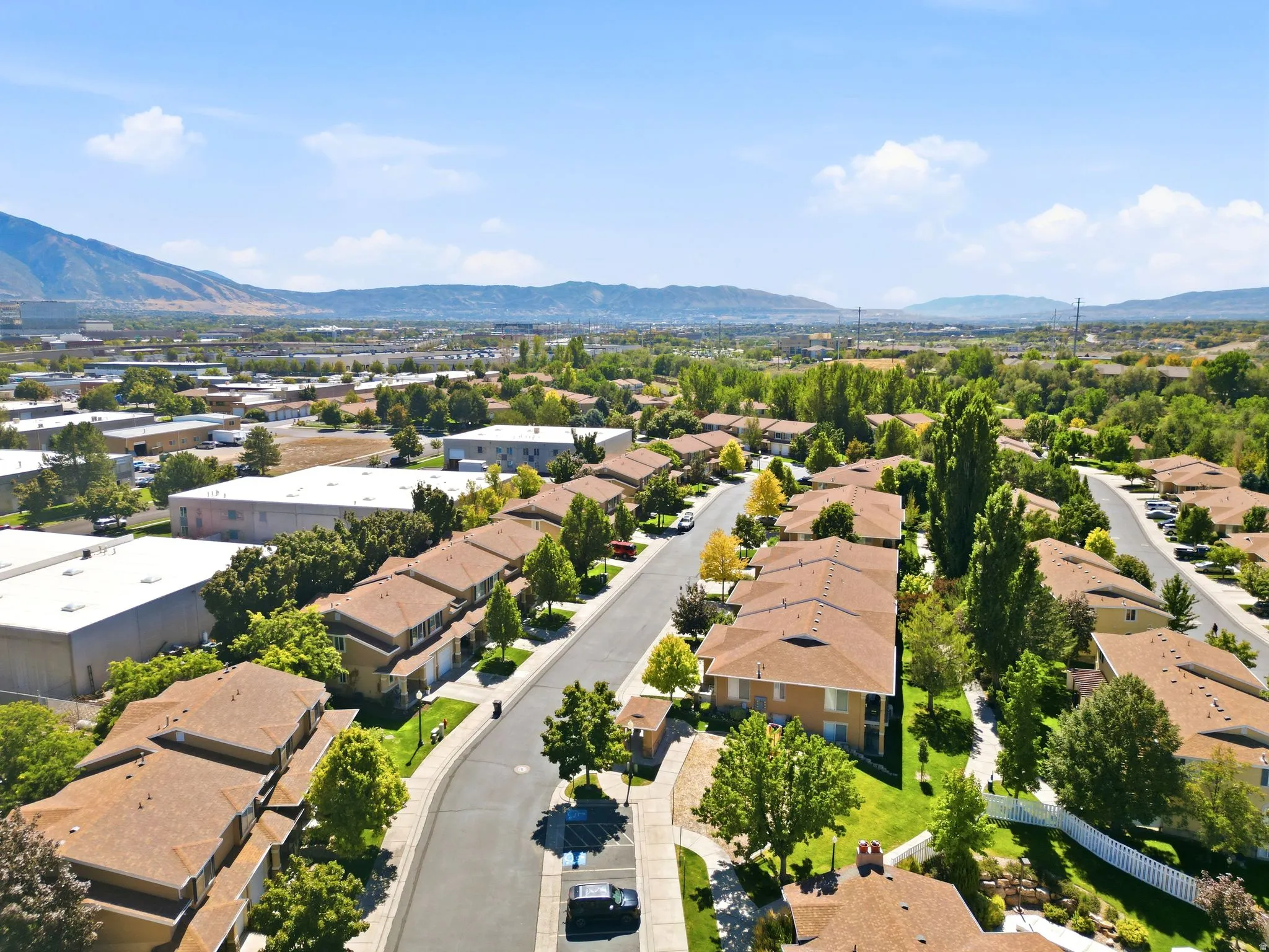 Neighborhood featuring mature trees, paved streets, and mountainous terrain in the distance