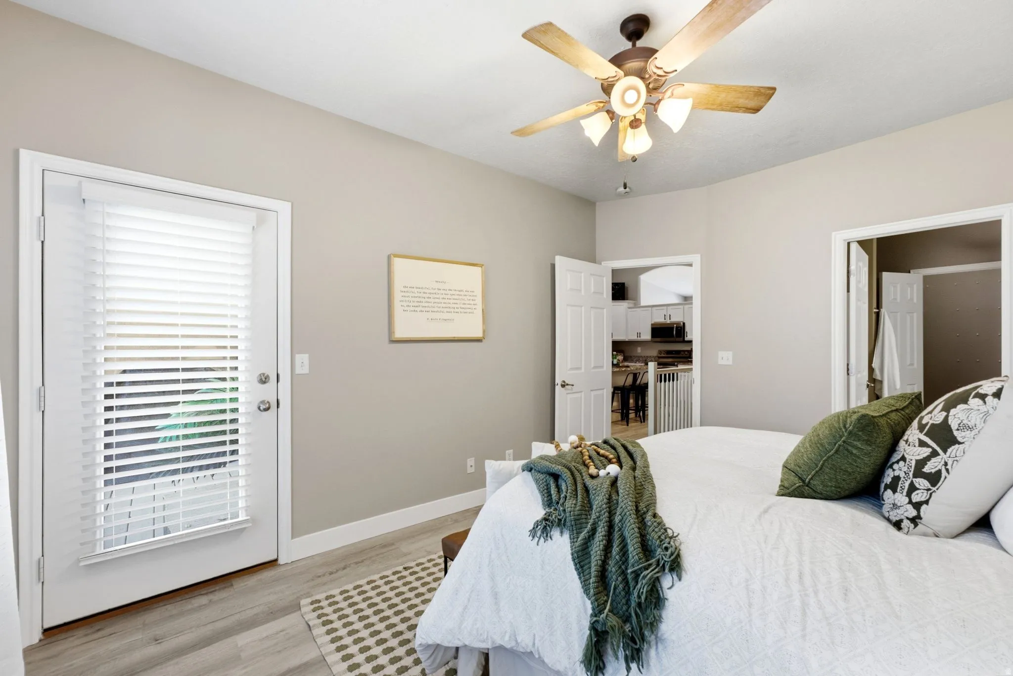 Wood-finish flooring, ceiling fan, white trim, and a patio door with blinds