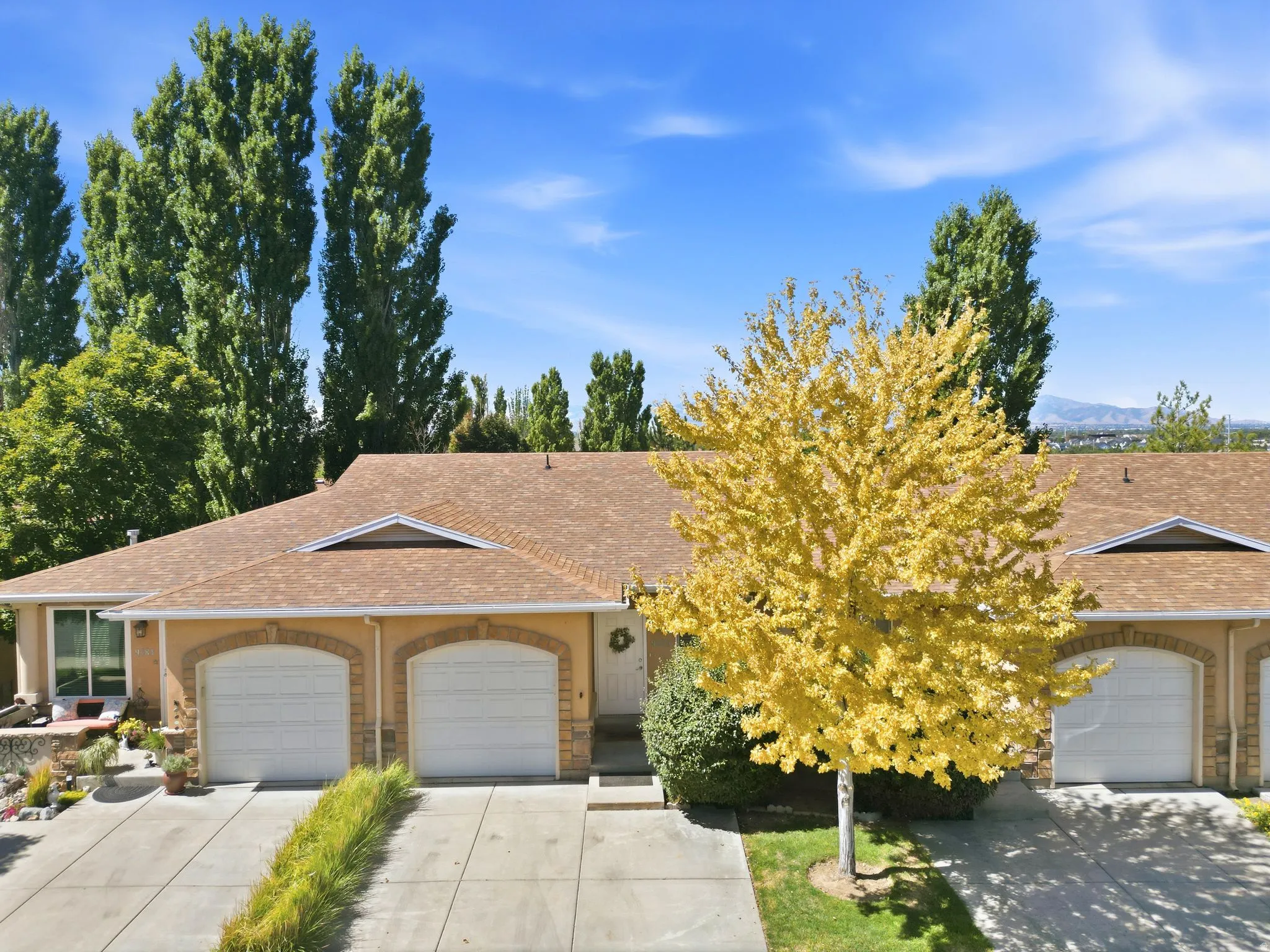 Attached two-car garage with arched entrances, concrete driveway, and a shingle roof