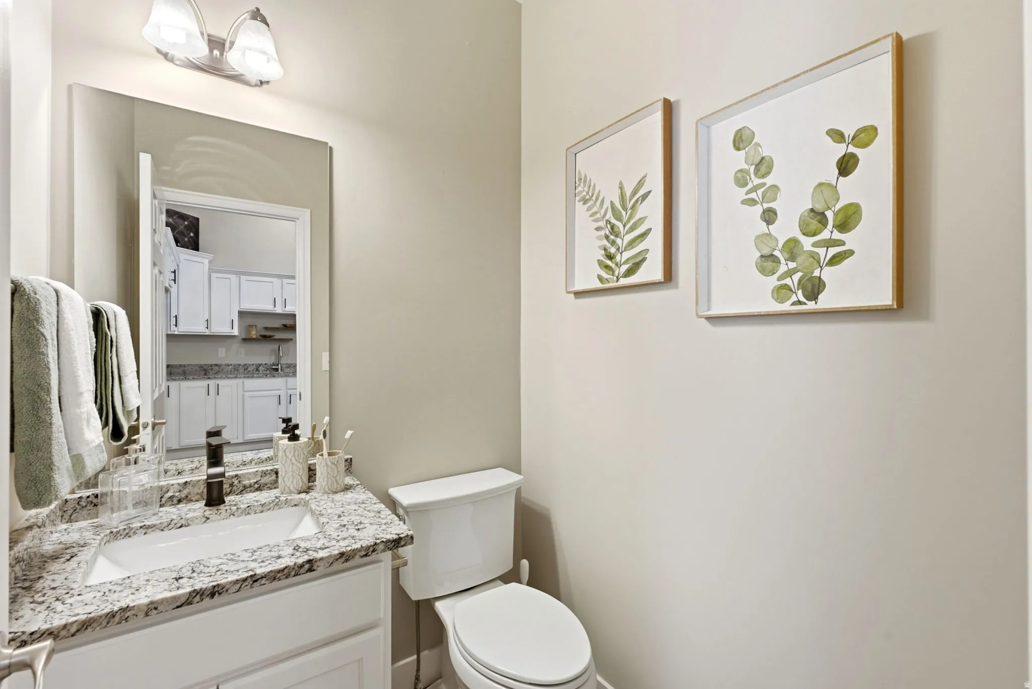 White vanity with granite-style countertop, undermount sink, and dark-finish faucet