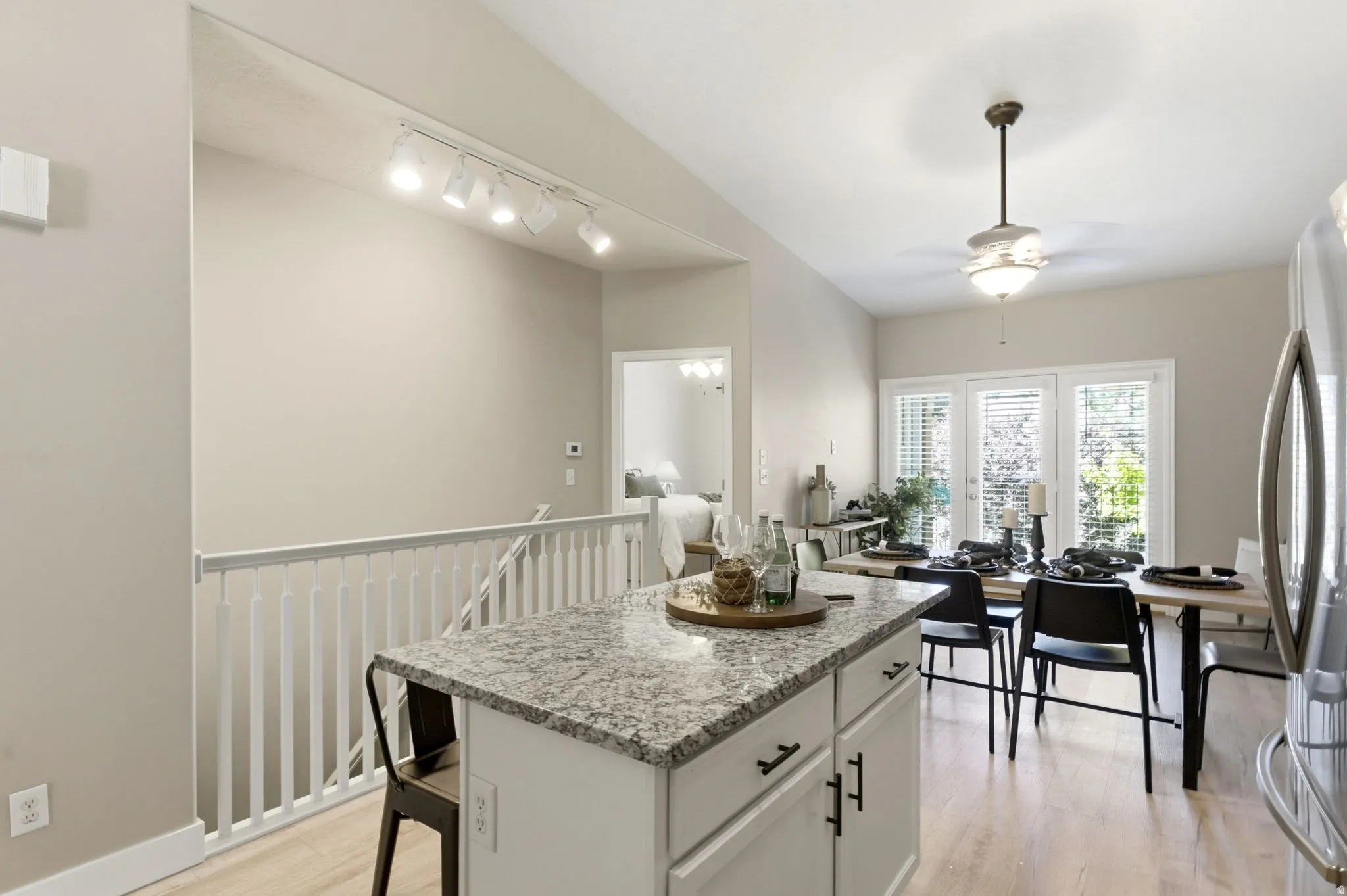 Kitchen island with granite countertop, wood-finish flooring, dining area with pendant light fixture, and French doors