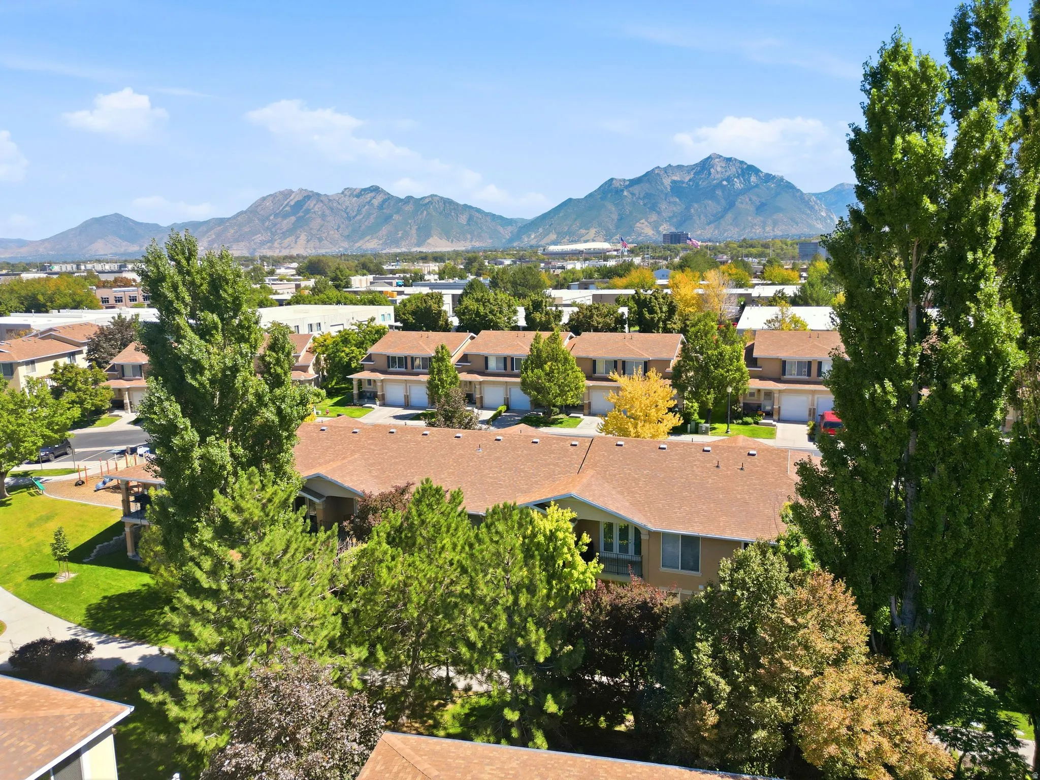 Community setting with townhomes, mature trees, and mountainous background
